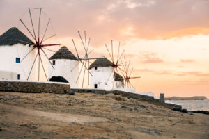 Iconic windmills perched along the shores of Mykonos at sunset