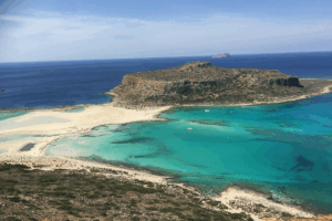 Cliff island in Crete surrounded by crystal blue waters