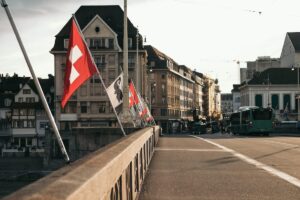 Switzerland flags over bridge in Basel, with buildings and city behind