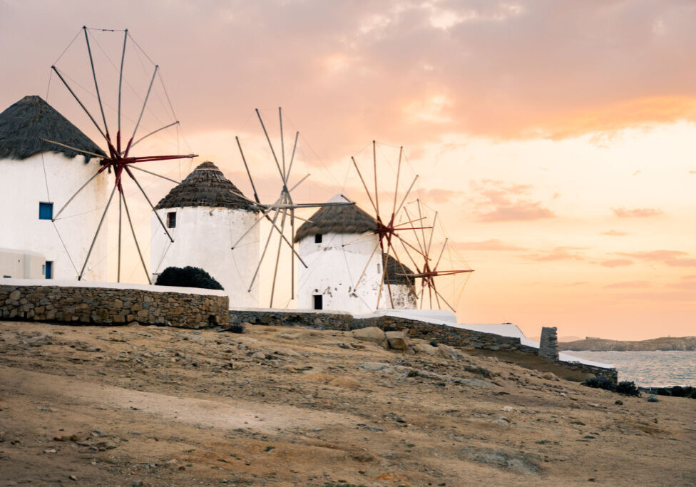 Iconic windmills perched along the shores of Mykonos at sunset