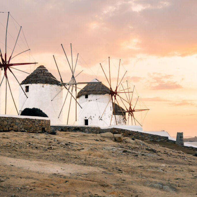 Iconic windmills perched along the shores of Mykonos at sunset