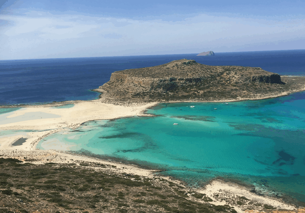 Cliff island in Crete surrounded by crystal blue waters