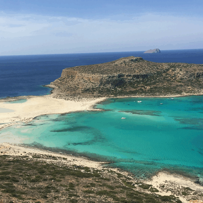 Cliff island in Crete surrounded by crystal blue waters